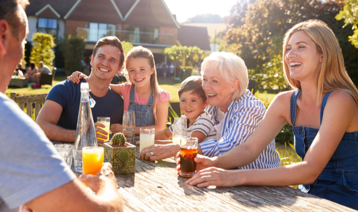 A smiling family sitting around a garden table.
