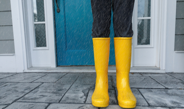 Someone standing outside their front door wearing yellow wellies.