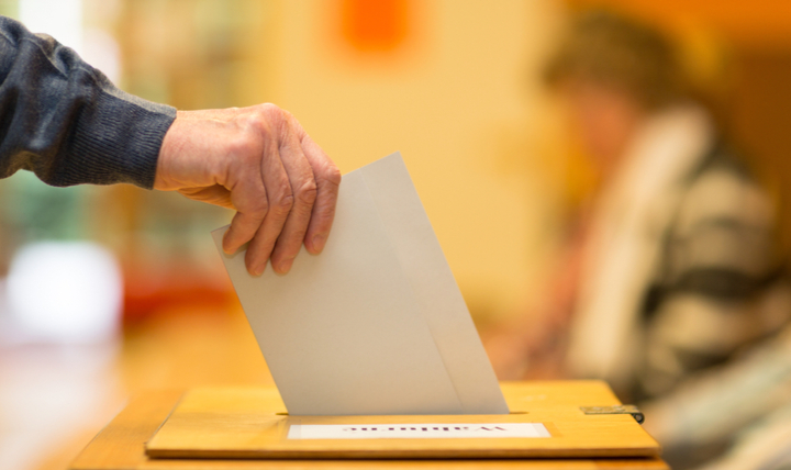 A man putting a ballot paper into a ballot box.