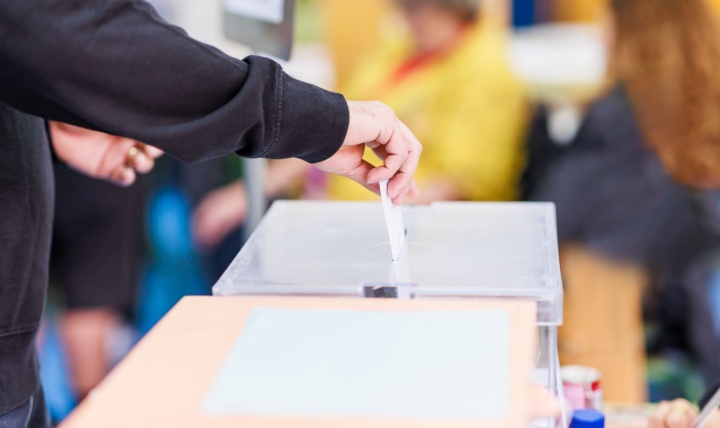 A man voting using a ballot box.