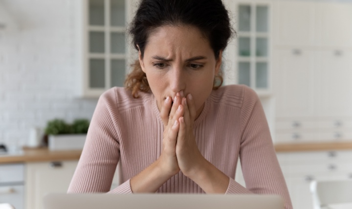 A woman looks at her laptop in shock.