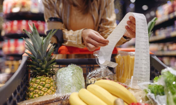 A woman looking at a receipt in a supermarket.