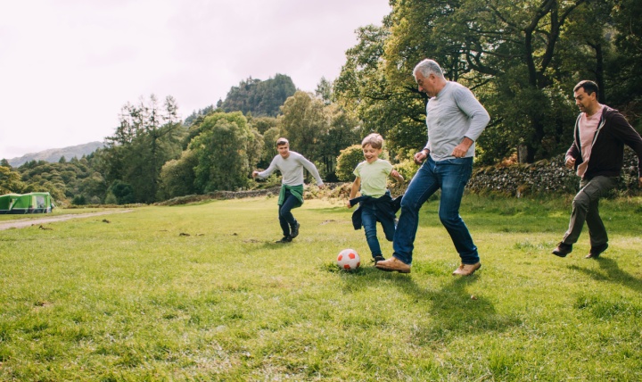 Multi-generational family playing football in a park.