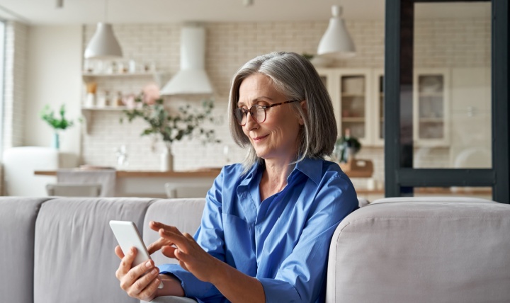 A woman in her 60s checking something on her mobile phone.