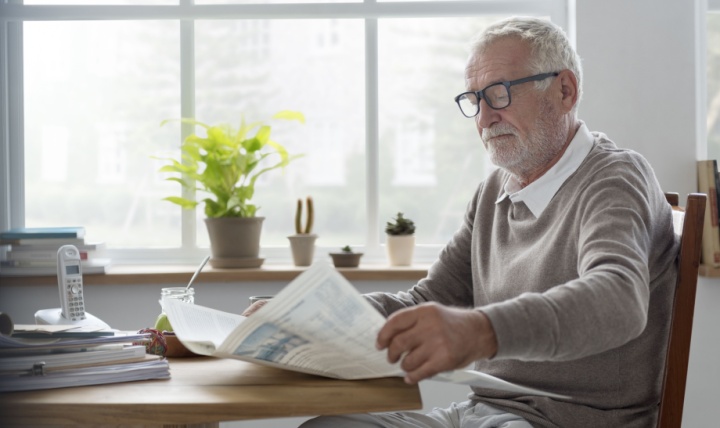 A man reading a newsletter at home.