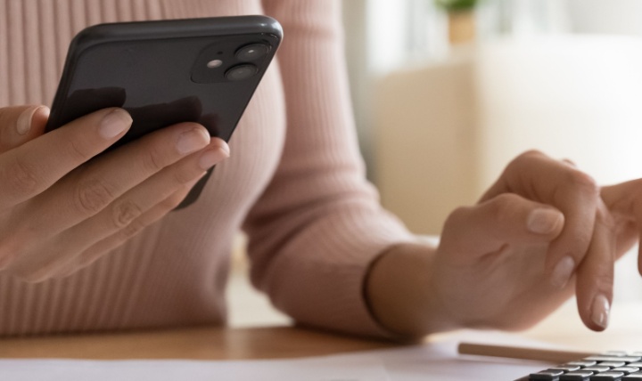 A woman using a phone and calculator.