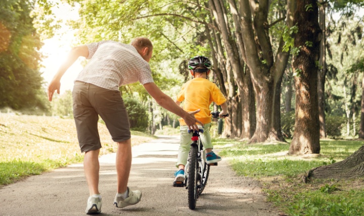 A father teaching a child to ride a bike.