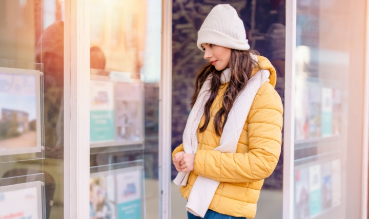 A woman looking at properties for sale in an estate agent window.