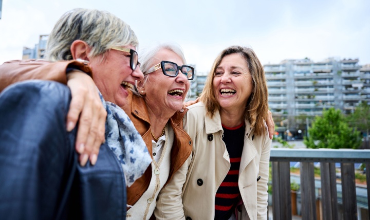 Three women with the around each other laughing.