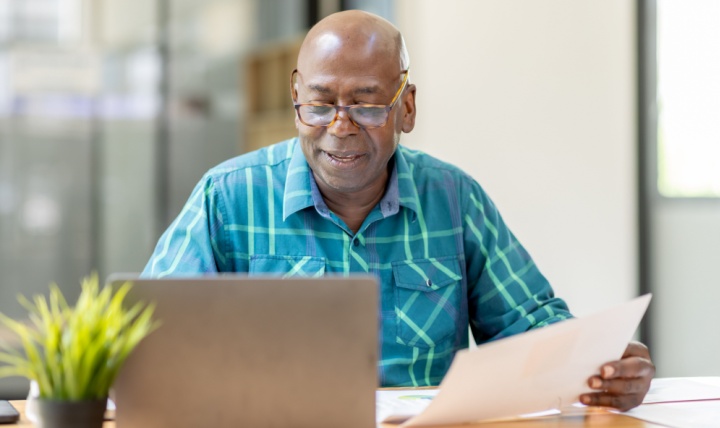 A man reviewing paperwork at his computer.