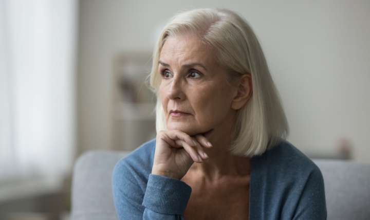 An older woman looks pensively off to one side.