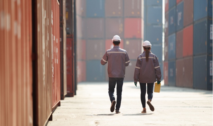 Two workers walking between shopping containers.