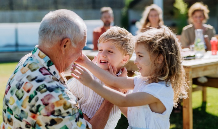 A grandfather playing with his grandchildren outdoors.