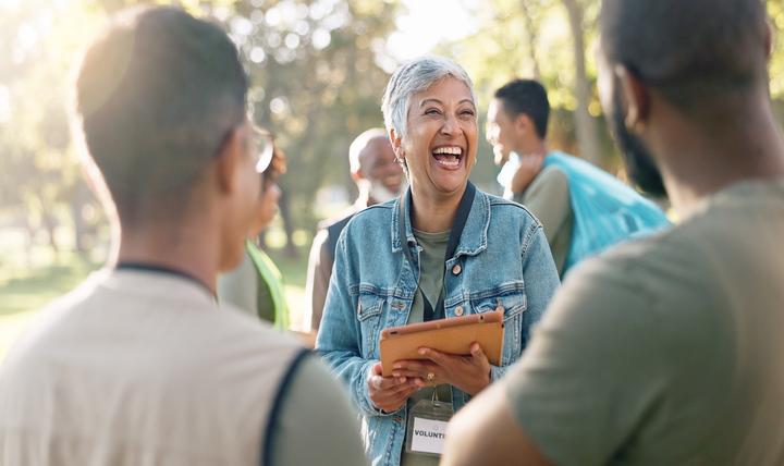 A woman with a clipboard volunteering at an event in a park.
