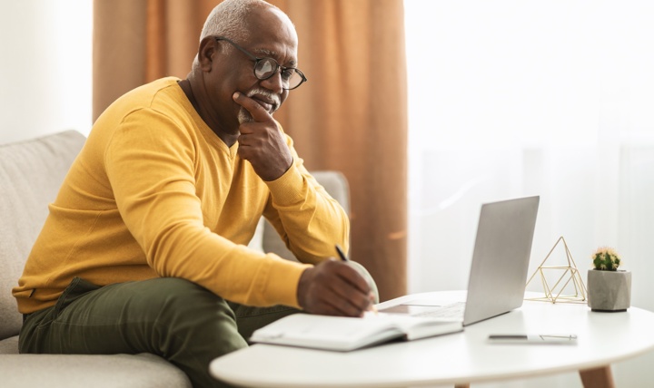 A man writing notes at a coffee table.