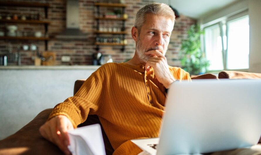 A man in his 50s thinking while using a laptop