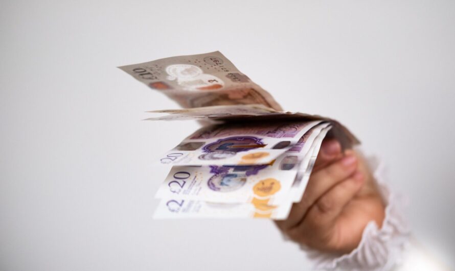A hand holding UK bank notes.