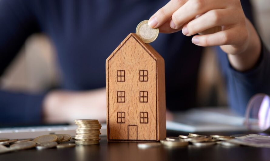 A person placing coins into a moneybox shaped like a house.