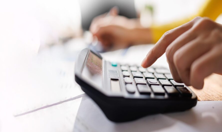 A person using a calculator while reviewing paperwork.